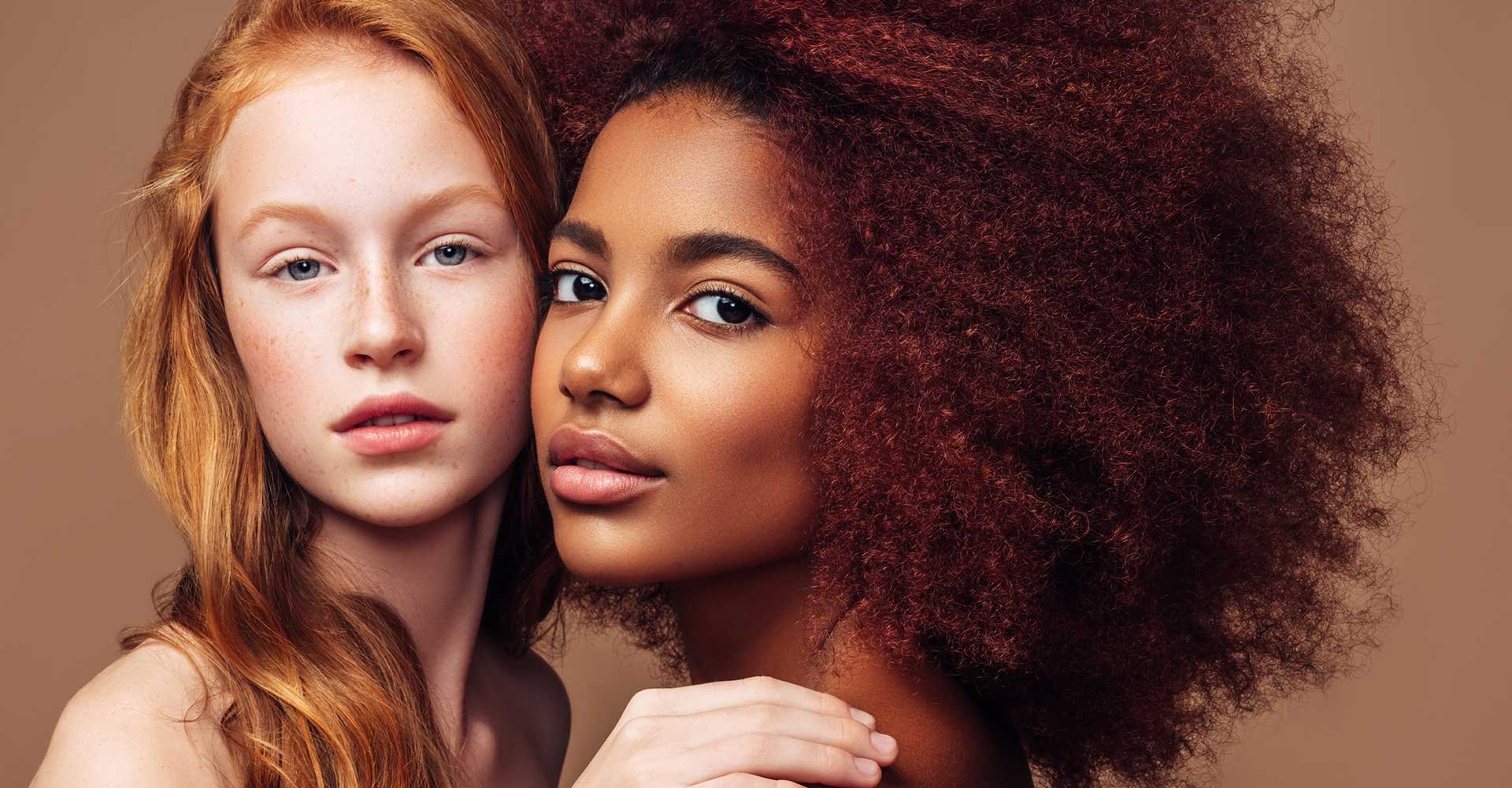 Dupla De Modelos Uma Ruiva Com Cabelo Liso E Outra Negra Com Volumosos Cabelos